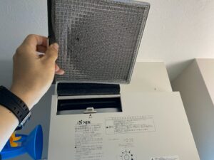 本体のメンテナンスカバーを開け、内部のメッシュフィルターを取り出す様子。