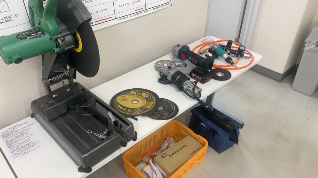 講習会場のテーブルに並べられたグラインダー、切断機、各種砥石、エアー工具などの教材