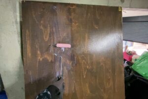 ローラーバケを使ってコンパネの表面にワックスを塗装している様子。