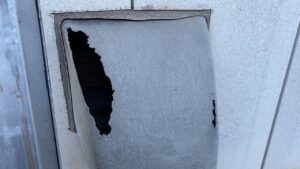劣化により大きく破損し穴が開いた古い換気フード。交換工事が必要な状態。