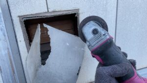 グラインダーで古い換気フードの残骸をカットしている様子。