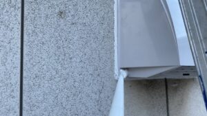 新しい換気フードの周囲にコーキングを打ち込み防水処理をしている様子。