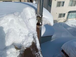 雪の重みがのしかかったステンレスの煙突