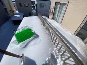 札幌市内での地面の除雪作業のビフォー写真。雪に埋まったバルコニー。