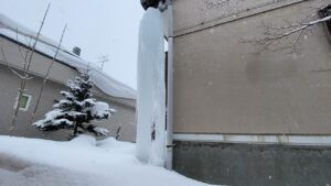 住宅の隙間に自立した巨大な氷の柱の全景。圧迫感が凄い。