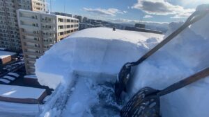 雪庇を下に落とさず、スコップで内側へすくい上げる繊細な作業風景