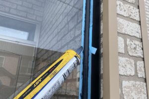 黒いコーキングを慎重に打ち込んでいる作業風景