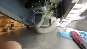 洗濯機の底部でホースの向きを変える作業