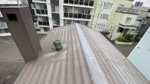 三角屋根の上で集合煙突の掃除を行う便利屋七道