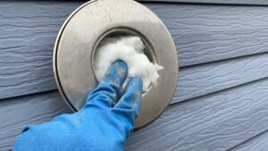 煙突穴の奥に断熱材（グラスウール）を敷き詰めている様子