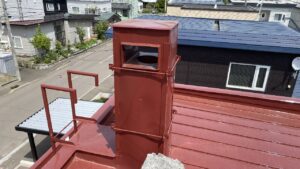 屋根の上に上り集合煙突の上部から掃除・点検する様子