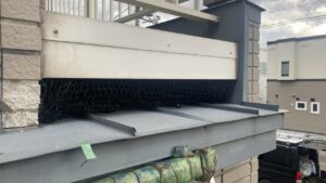 ベランダのすのこと板金屋根の暗い隙間の奥に、ぴったりと頑丈に取り付けられた黒い金網のアフター写真