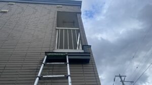 2階のベランダに向けて外壁に長い梯子を立てかけ、これから作業を開始する施工前の写真