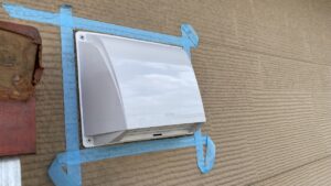 新しく設置した換気フードの周囲に、綺麗にコーキングを塗るために丸く貼られた白いマスキングテープの養生写真