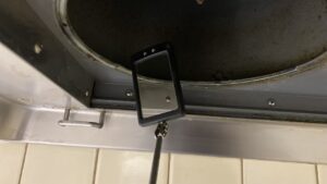 伸縮棒の先についた丸い手鏡を換気扇内部の狭い隙間に差し込んで死角を慎重に映し出している作業中の写真