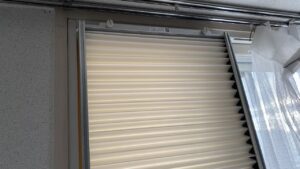 取り付けた窓用エアコンの上部の蛇腹パッキンと、上枠がネジで窓サッシにしっかり固定されている様子の拡大写真