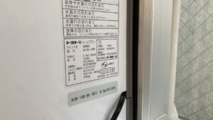 エアコン本体の右側面に貼られた仕様シールの拡大写真。型式ACW-16R、冷房消費電力523/598W、2026年製などの製品スペックが記載されている