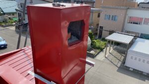 作業前の江別市のお客様宅の集合煙突。黒い塗装が施された四角い煙突で、側面に排気用の開口部がそのまま空いており、鳥が簡単に入り込める状態になっている