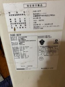 ボイラーの側面に貼られている特定保守製品の製品名(OQB-307F)や製造年月(2014年1月)、設計標準使用期間(10年)などが記載されたシールのアップ写真
