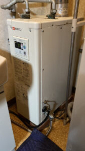 洗面所に設置されているノーリツ(NORITZ)製の白い屋内用石油給湯器(ボイラー)の全体写真