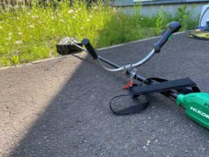 アスファルトの上に置かれた、鮮やかな緑色のHiKOKI(ハイコーキ)製バッテリー式刈払機の全体写真