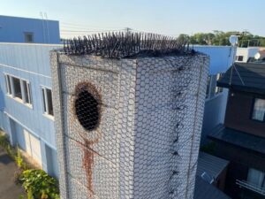 2階の屋根の集合煙突の開口部に、鳥が入れないよう金網が頑丈に貼られ、さらにその上にプラスチック製のハト除けトゲトゲシートが隙間なく設置された完成写真