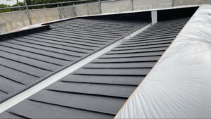 屋根全体にマットな黒色の錆止め塗料が塗り終わり、下塗り工程が無事に完了した屋根全景の写真