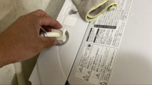 洗濯機の給水ホースを取り外している様子