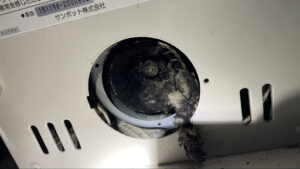 大量のホコリがプロペラに絡みついているストーブ背面のファンの写真